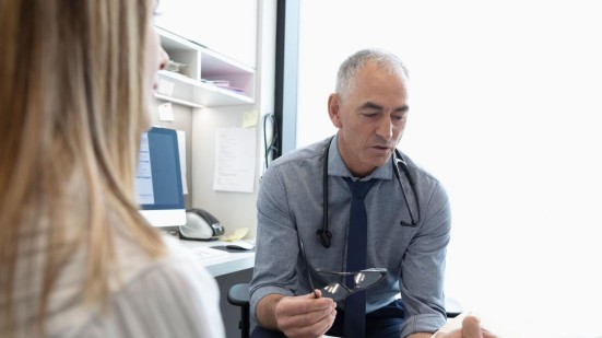 Arzt bespricht mit Patient und Begleitung die Diagnose