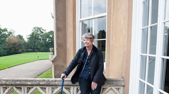 Frau mit Sauerstoffgerät vor Haus