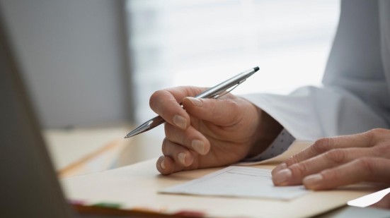 Arzthand beim Unterschreiben eines Attests