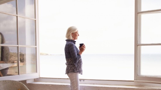 Frau am offenen Fenster mit Blick aufs Meer