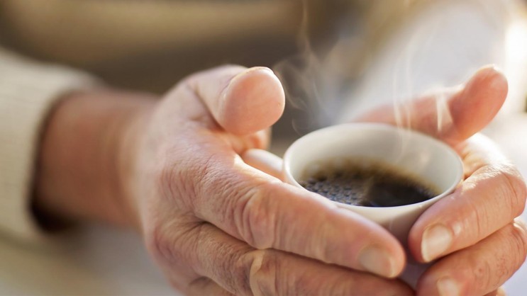 Frauenhände umschließen Kaffeetasse
