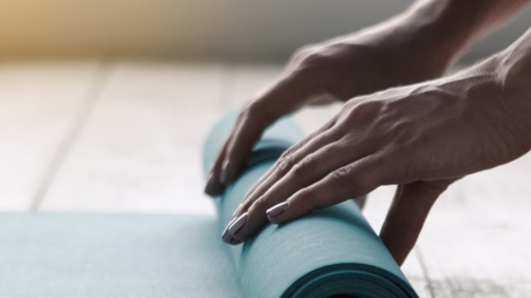 HändYogae, die eine Yogamatte ausrollen