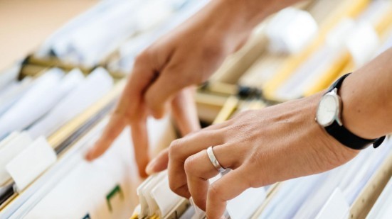 Hand blättert durch Akten