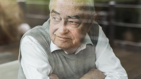 Senior blickt durch ein Fenster