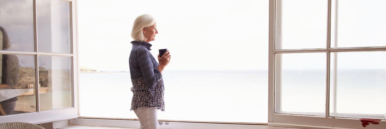 Frau am offenen Fenster mit Blick aufs Meer