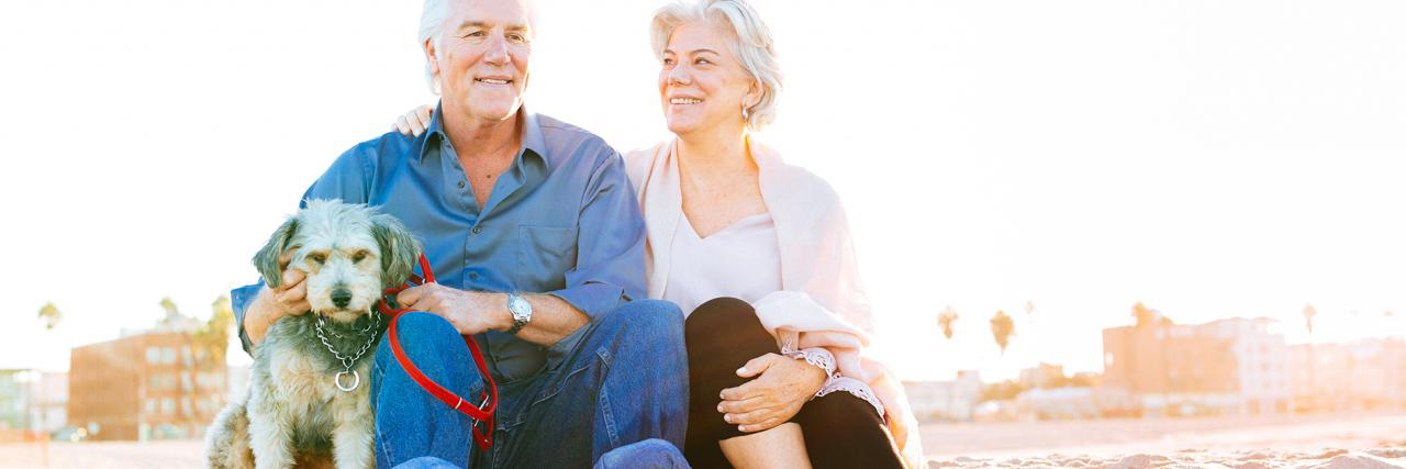 Aktives Paar mit Hund am Strand