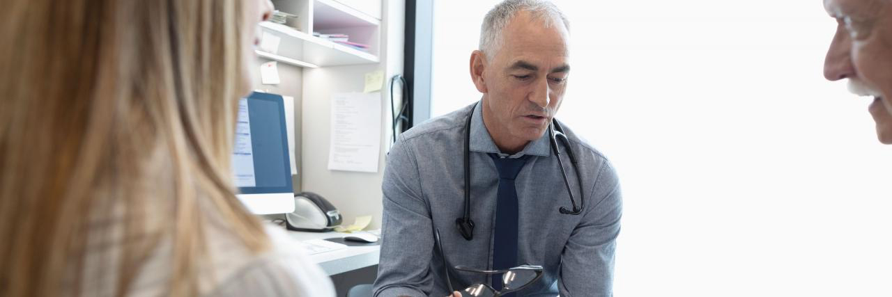 Arzt bespricht mit Patient und Begleitung die Diagnose