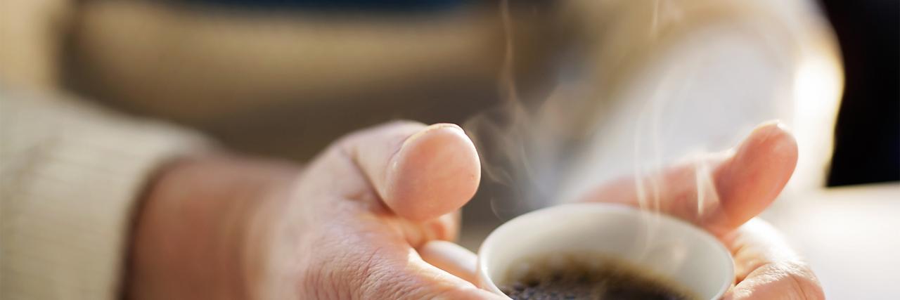 Frauenhände umschließen Kaffeetasse