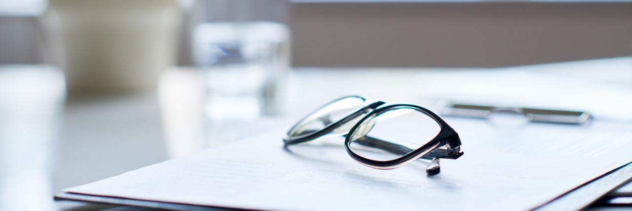 Tisch mit Akten und einer Brille