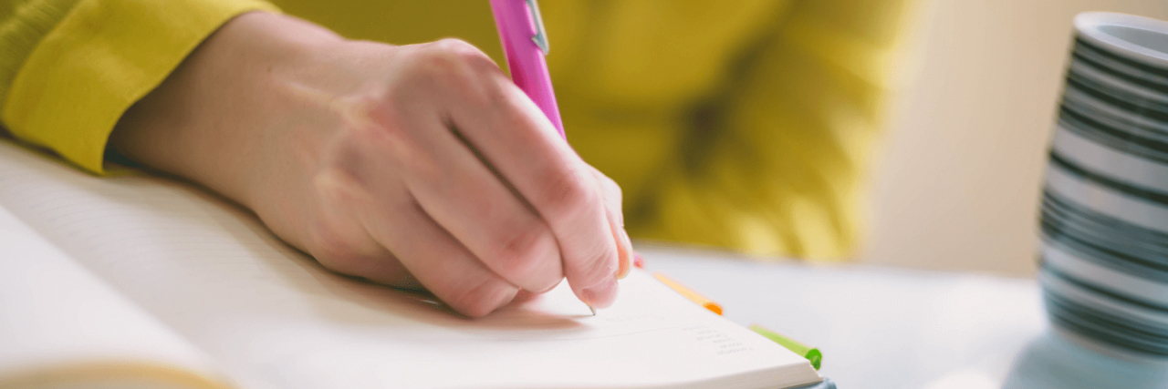 Hand mit Stift, die in ein Notizbuch schreibt
