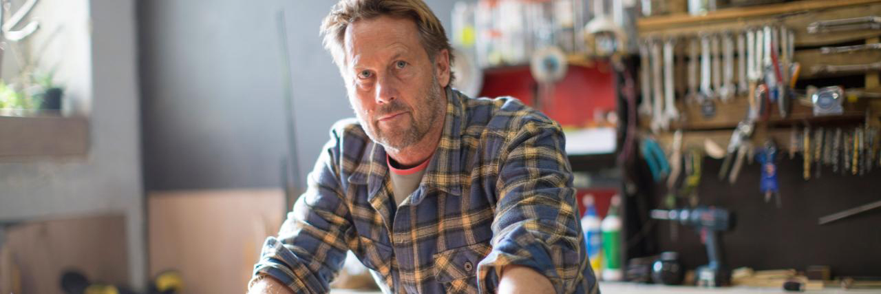 Mann in der Werkstatt, der in die Kamera blickt